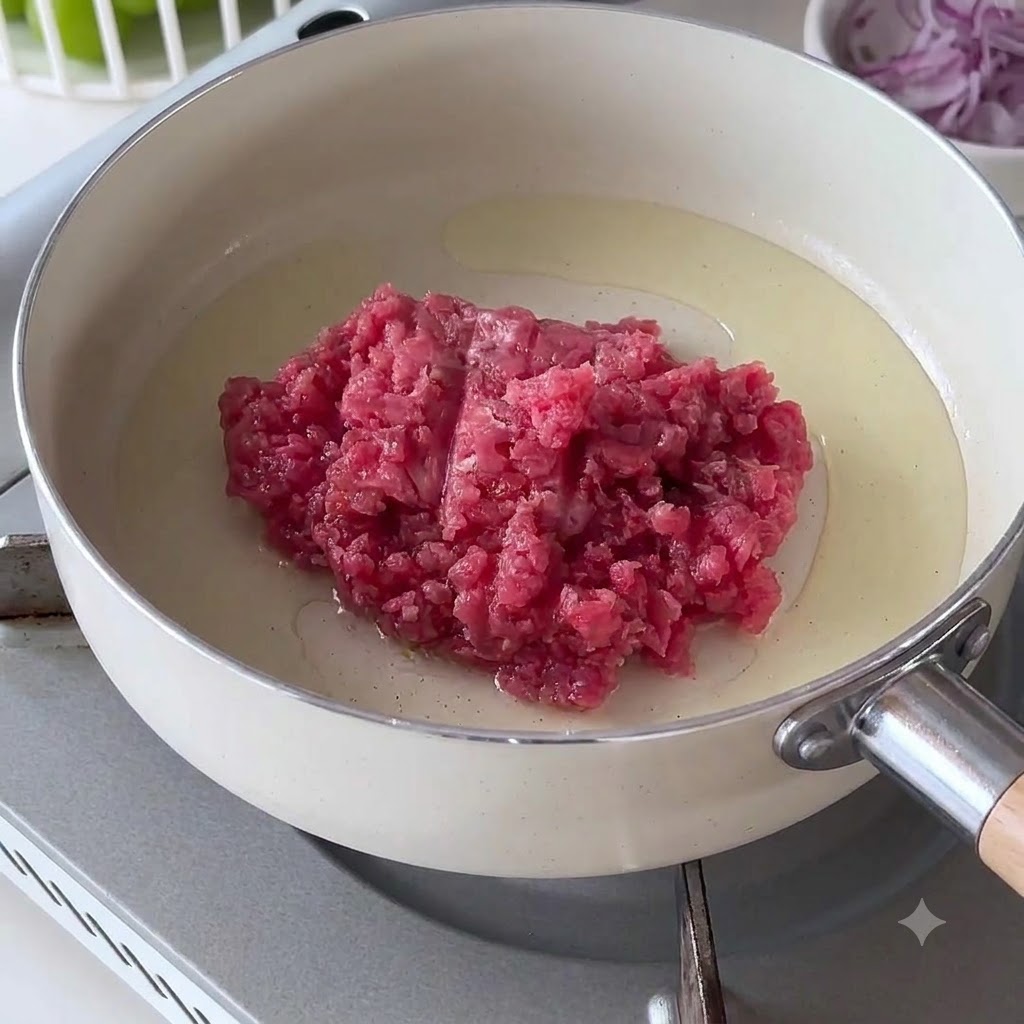 Bœuf haché cru placé dans une poêle blanche chaude avec de lhuile.