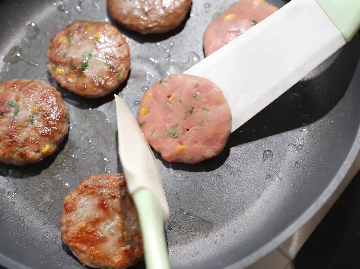 Galettes retournées dans la poêle à laide dune spatule, révélant des surfaces bien dorées cuites à feu doux.