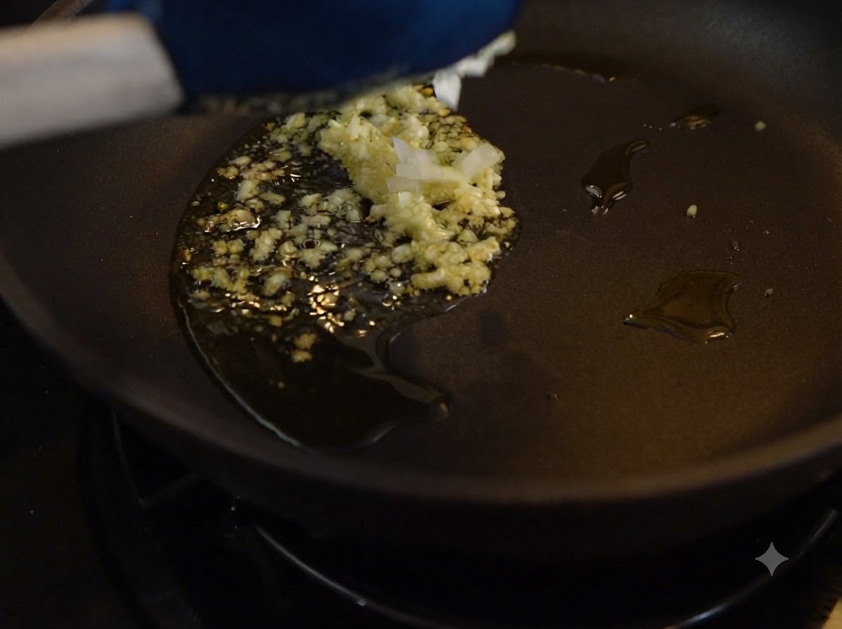 De lail haché et des oignons cuisant dans lhuile à lintérieur dune poêle sombre.