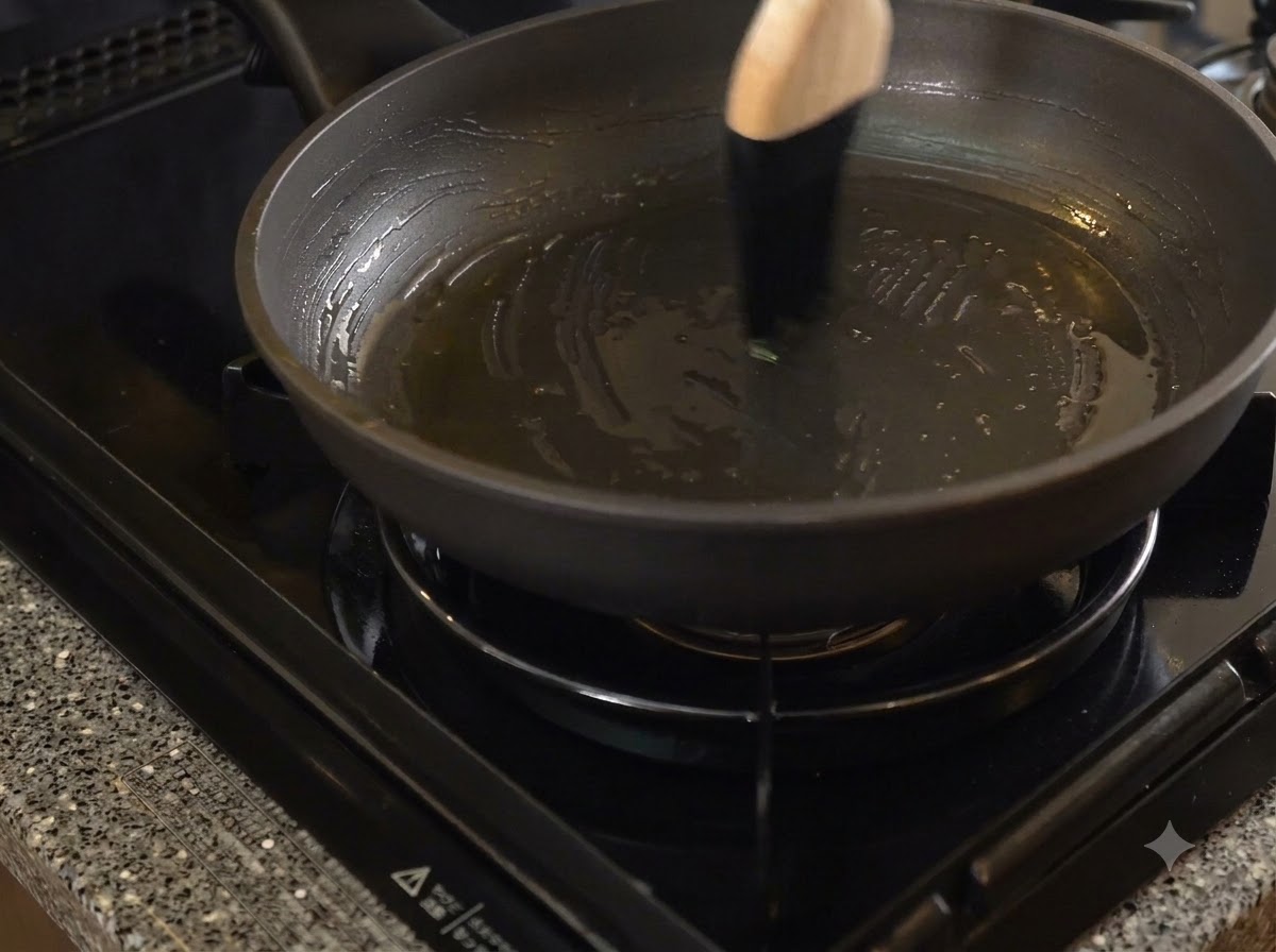 Une poêle antiadhésive sombre badigeonnée de saindoux à laide dun pinceau de cuisine à manche en bois.