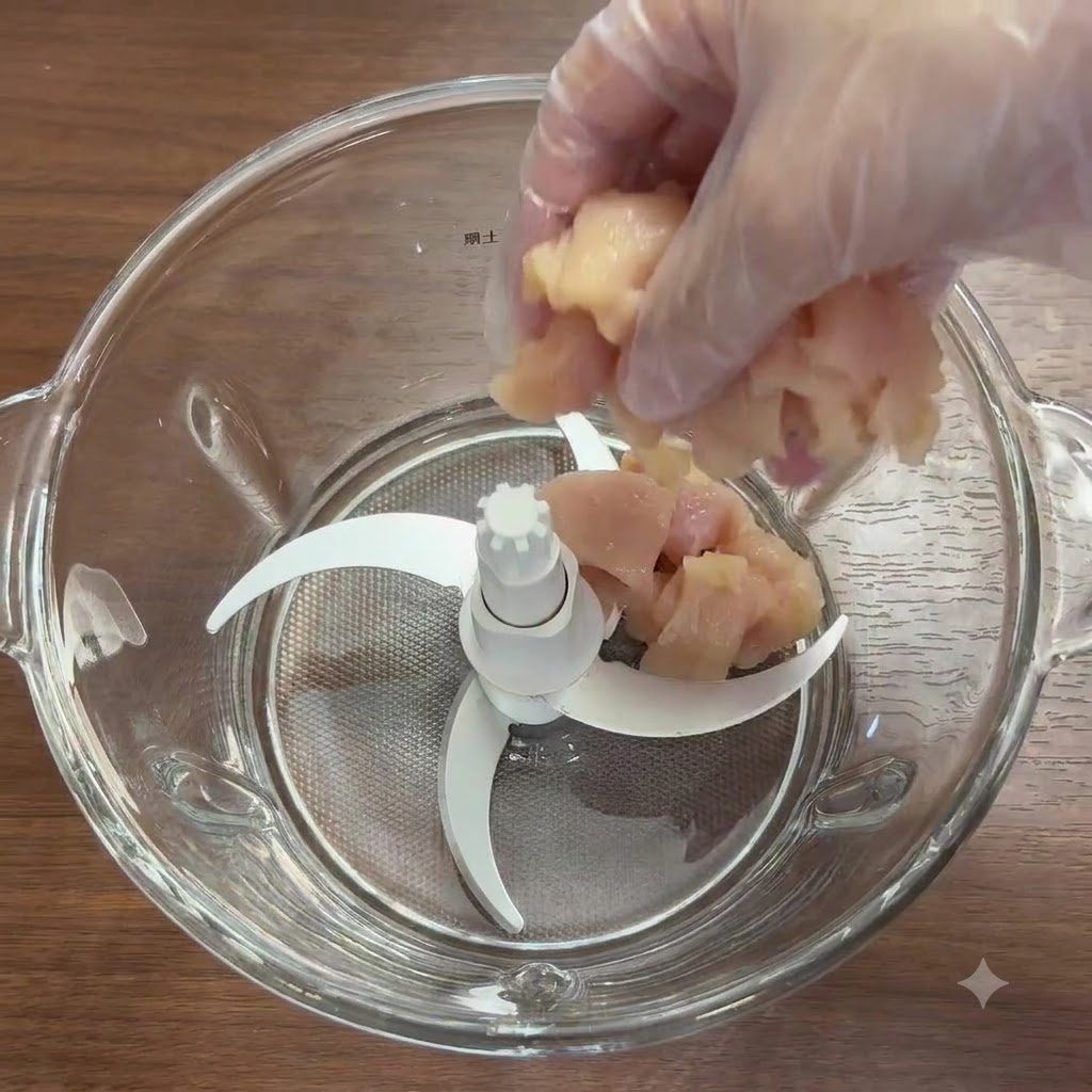 Morceaux de blanc de poulet et légumes frais dans le bol dun mixeur en verre avec les lames.