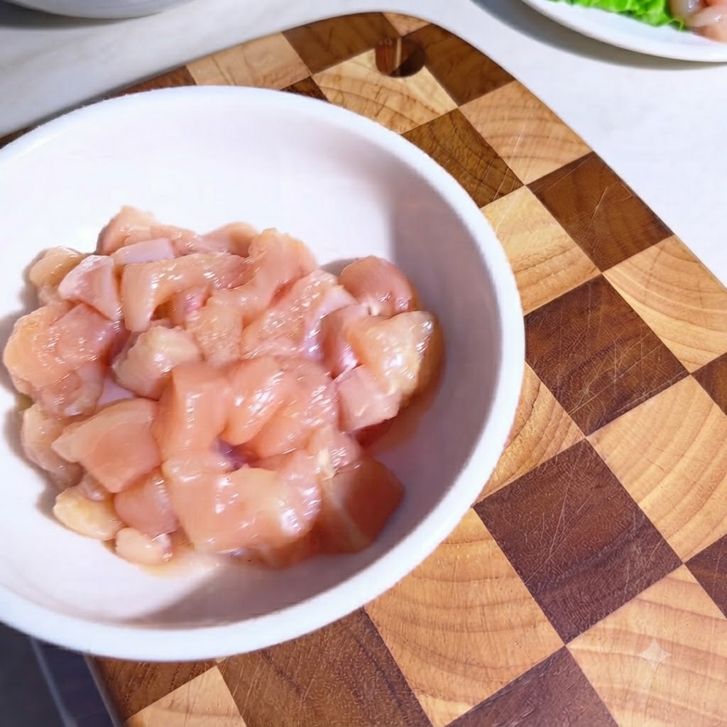 Morceaux de poulet cru dans un bol blanc enrobés dassaisonnements et dhuile dolive.
