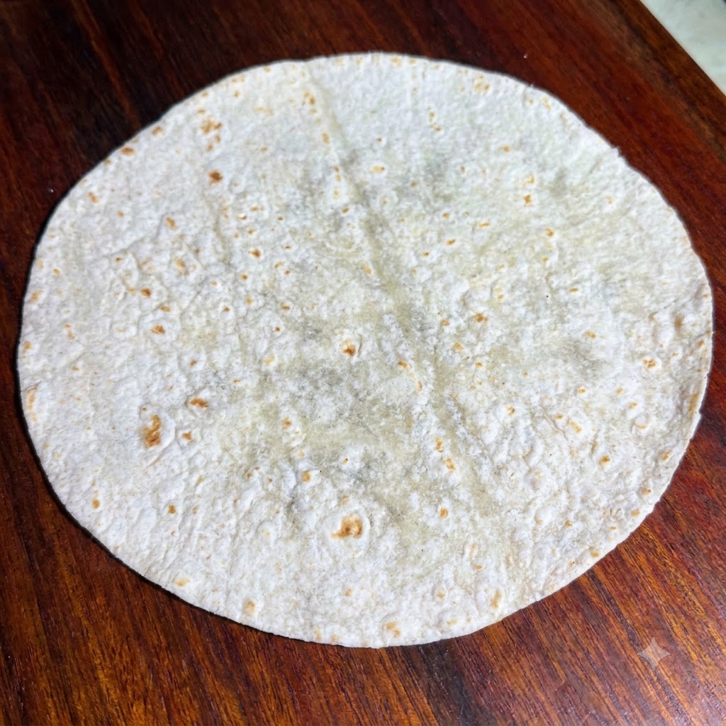 Feuilles de laitue verte fraîche disposées nettement sur le dessus dune tortilla de blé entier plate et ronde.
