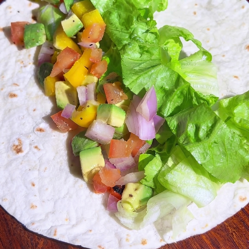 Morceaux de poulet cuits en dés répartis sur la garniture de légumes de la tortilla.