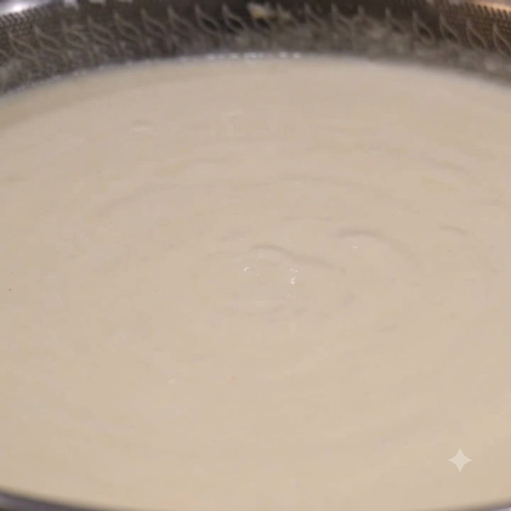 Une louche ramassant du chowder de palourdes blanc crémeux dun wok en train de mijoter.
