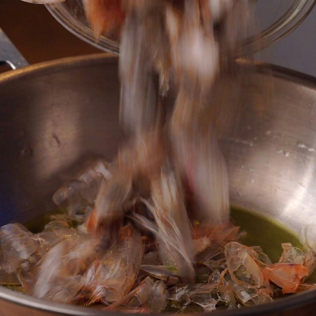 Des têtes de crevettes qui frient dans de lhuile à lintérieur dune marmite en métal profonde.
