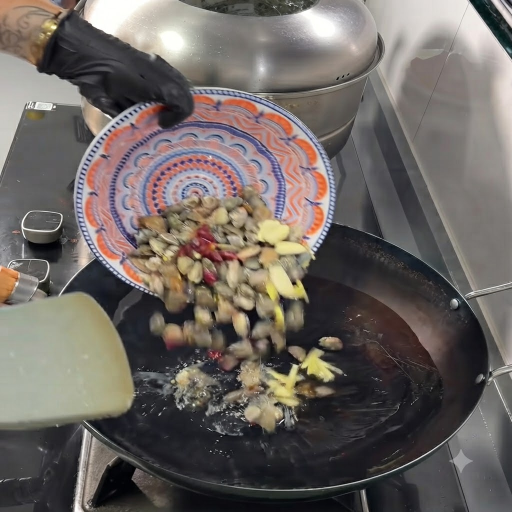Palourdes, ail tranché, gingembre et piments séchés tombant dune assiette dans le wok chaud.