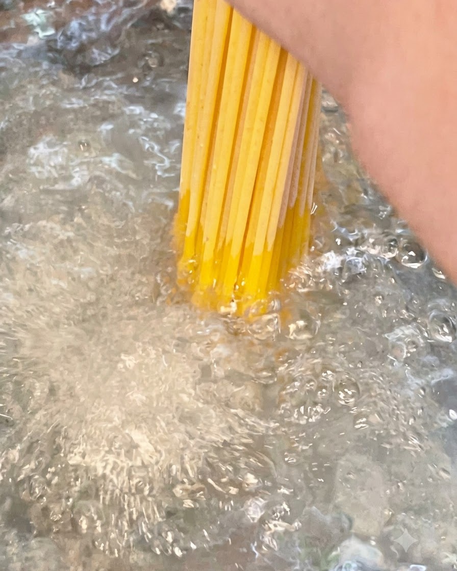 Un paquet de spaghettis secs plongés dans une casserole deau bouillante salée.