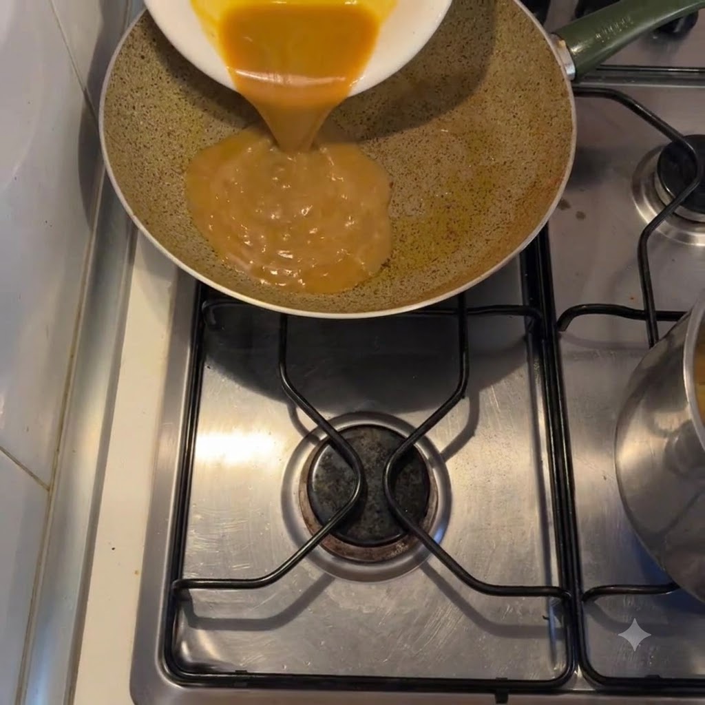 Une sauce dorée et épaisse est versée dune assiette blanche dans une poêle sur une cuisinière.
