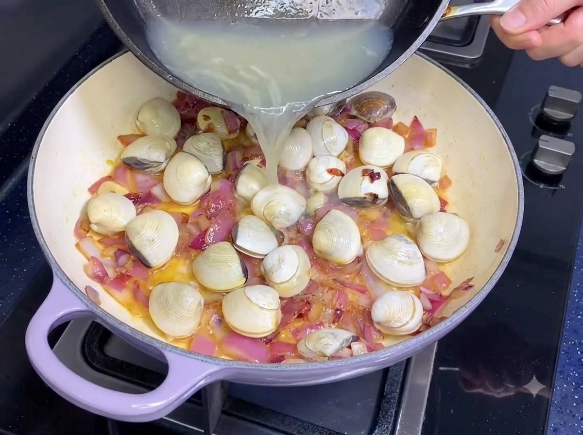 Du bouillon de palourdes versé dune poêle dans une casserole avec des oignons et de lail.