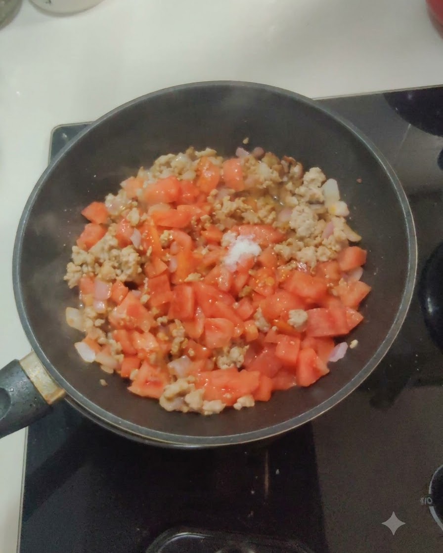 Du sel blanc et du sucre saupoudrés sur le mélange de tomates, doignons et de viande dans une poêle.