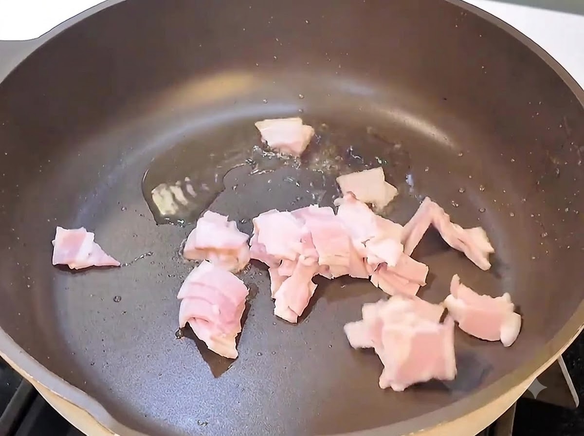 Lardons en train de rissoler et dorer dans une poêle sur le feu.
