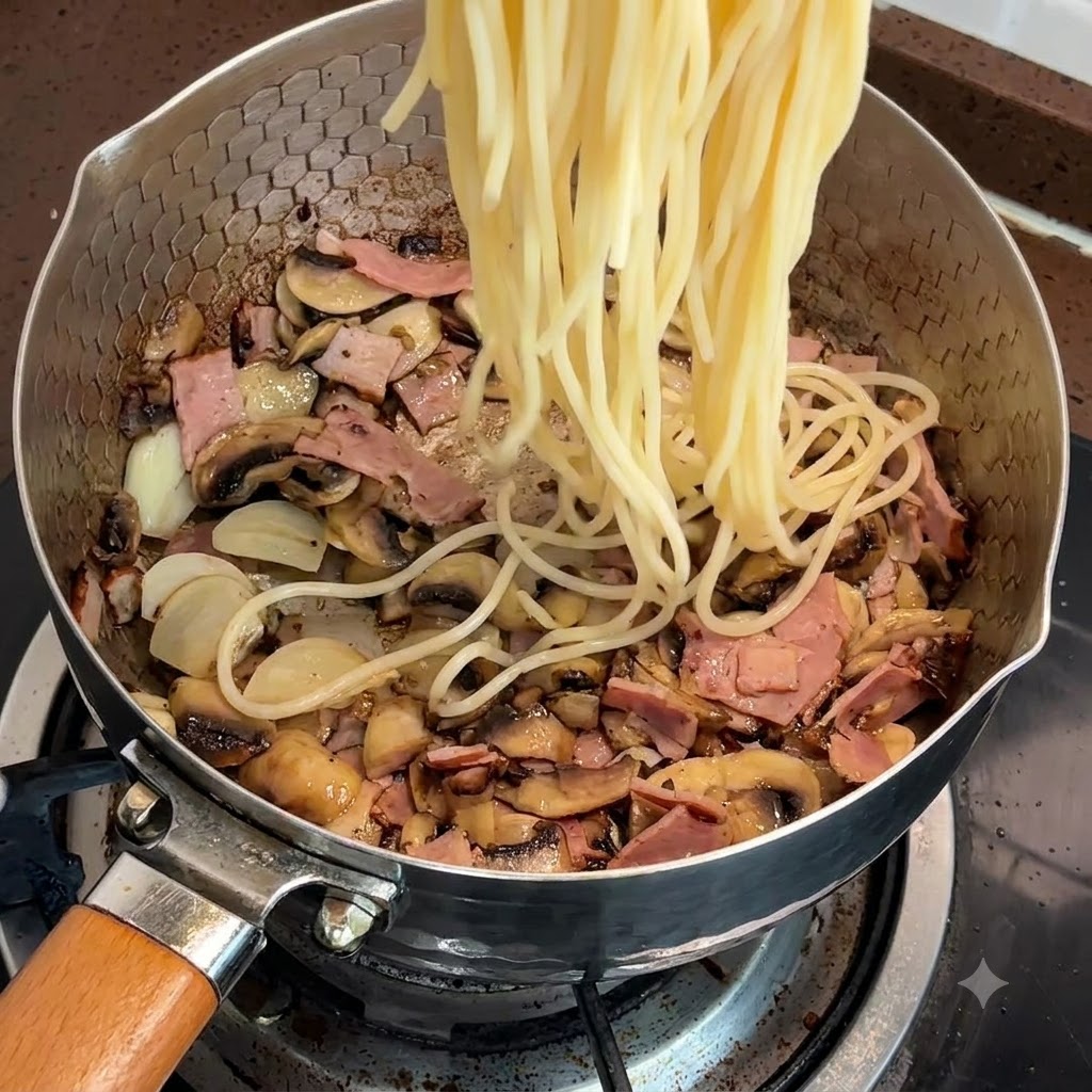 Des nouilles de spaghetti cuites ajoutées dans la poêle avec le bacon et les champignons.
