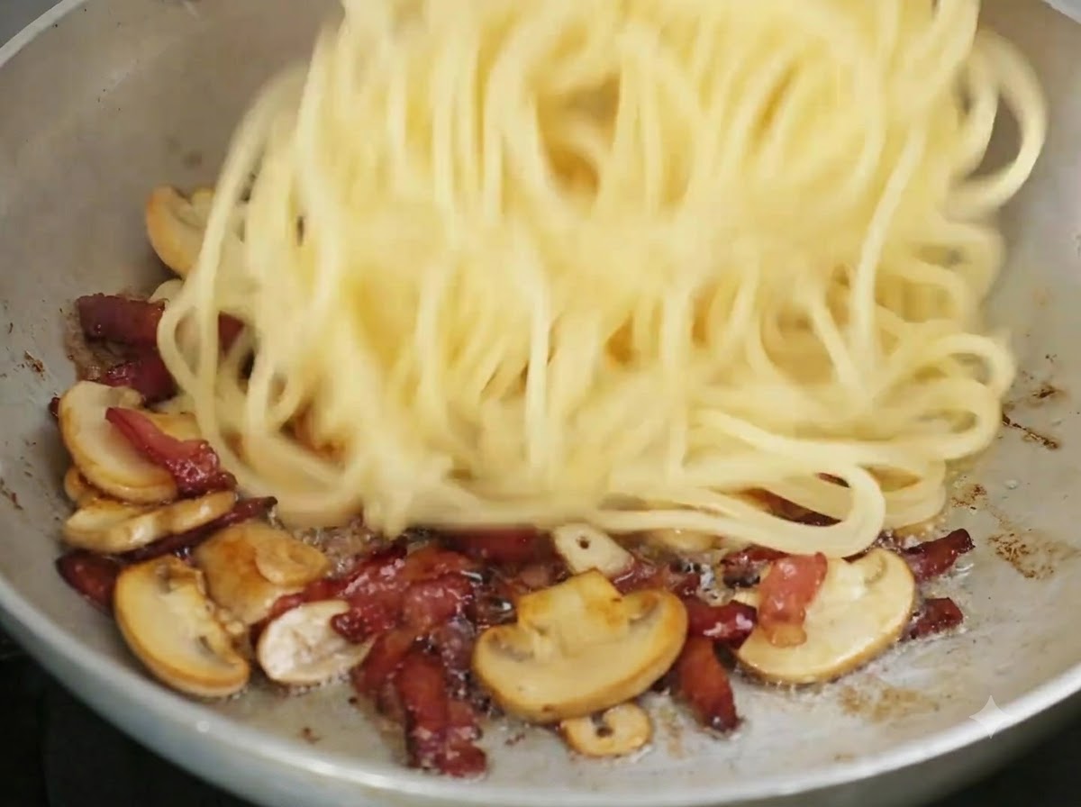 Spaghettis cuits ajoutés dans la poêle avec les ingrédients cuits.