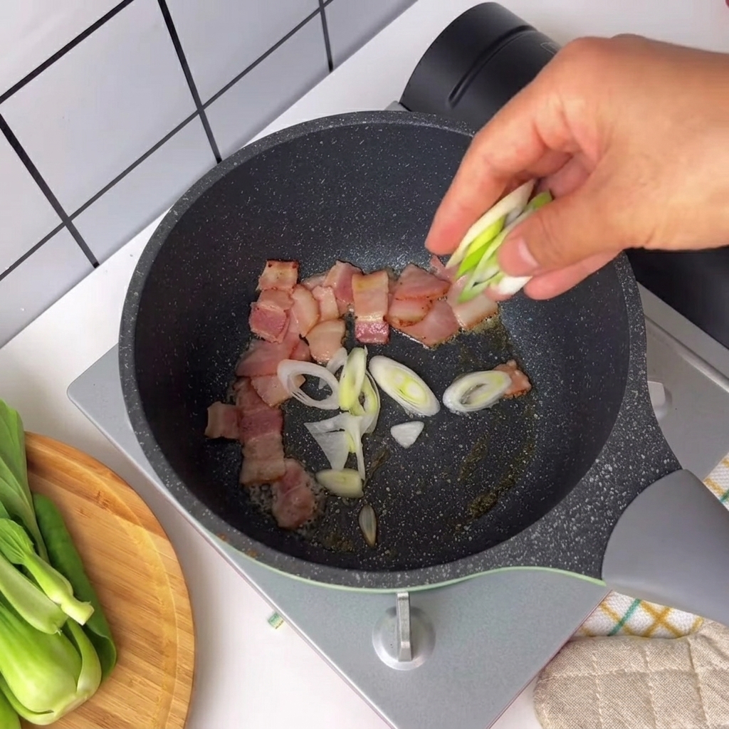 Morceaux doignons verts et piment saupoudrés dans une poêle avec des morceaux de bacon grésillants.