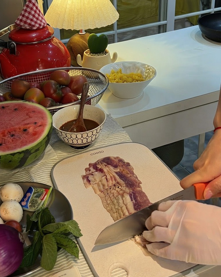 Un oignon rouge coupé en deux sur une planche à découper à côté dune assiette de champignons et de menthe fraîche.