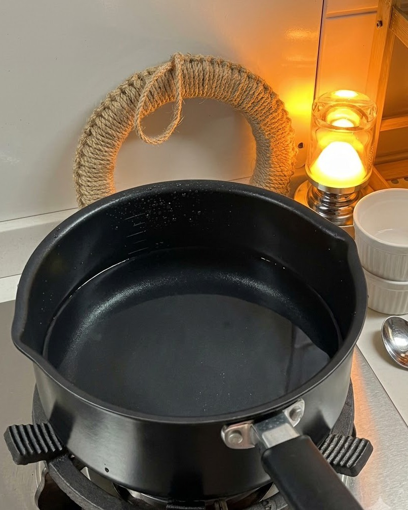 Pâtes fusilli sèches versées dans une casserole deau bouillante sur le feu.