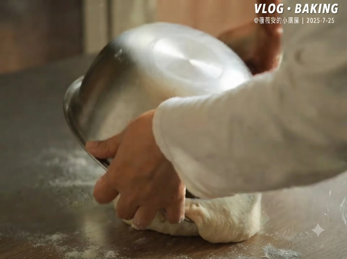 Un bol en métal retourné pour libérer la pâte à pizza fermentée sur un plan de travail fariné.