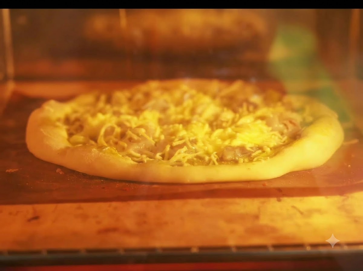 Une pizza en train de cuire sur une plaque à lintérieur dun four allumé avec des résistances chauffantes incandescentes.
