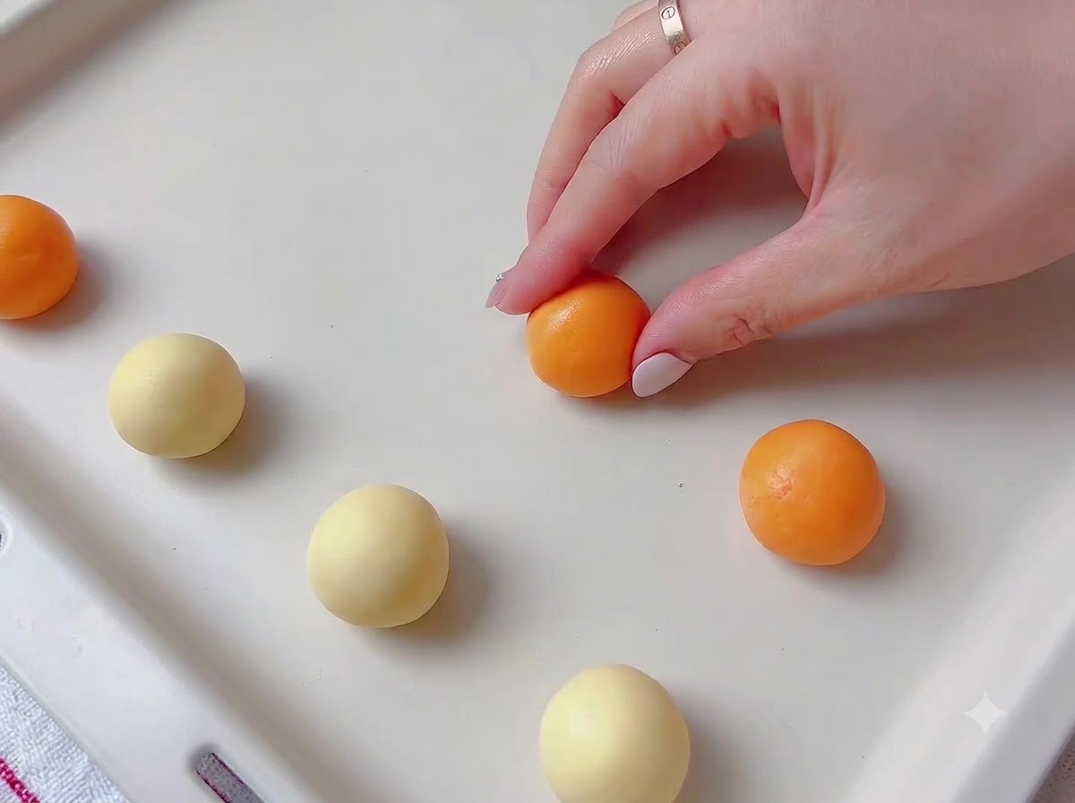 De la pâte à biscuits colorée façonnée en petites sphères régulières sur une surface propre.