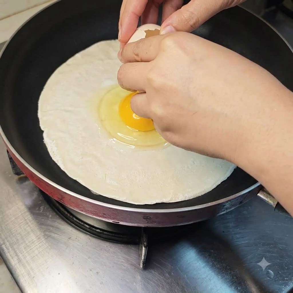 Un œuf cassé directement au centre dune crêpe à la ciboule crue dans une poêle.