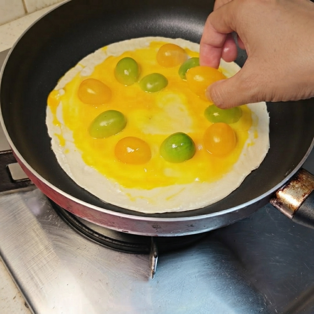 Des tomates cerises jaunes et oranges disposées en cercle sur la crêpe recouverte dœuf.