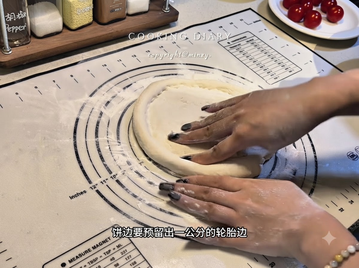 Des mains façonnant les bords dune base de pâte à pizza plate sur un tapis en silicone pour former un rebord surélevé.