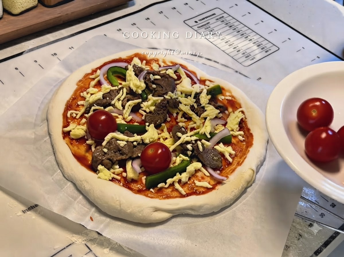 Une pizza entièrement assemblée avec du fromage, du bœuf, des poivrons, des oignons et des tomates cerises entières sur du papier sulfurisé.