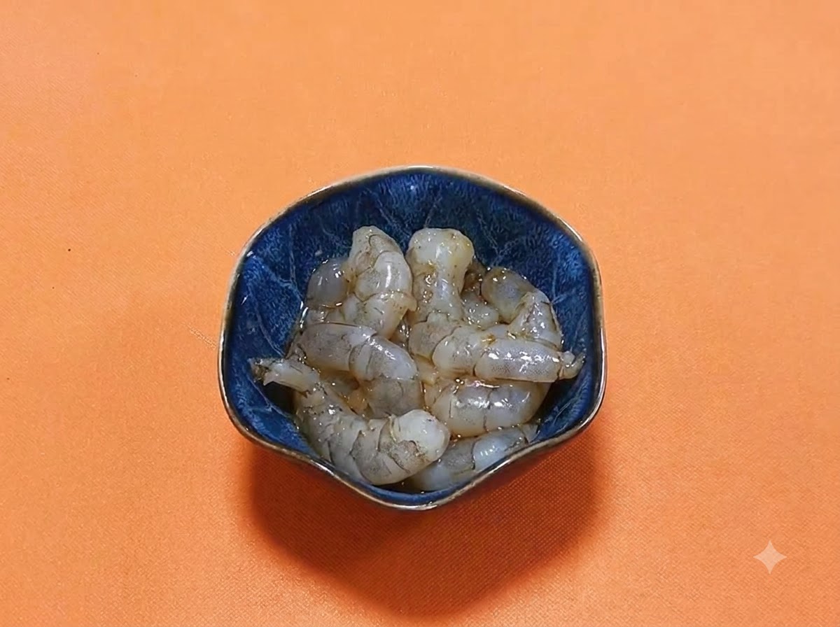 Crevettes crues decortiquees reposees dans un bol bleu fonce avec une marinade brillante de sauce soja foncee et depices.