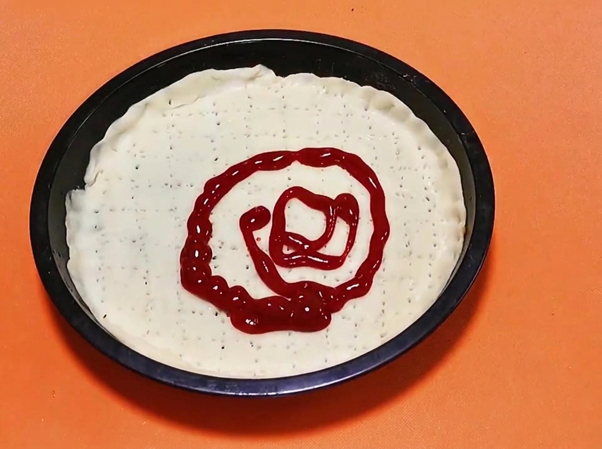 Un motif en spirale de sauce tomate rouge vif verse au centre dune base de pate a pizza crue.