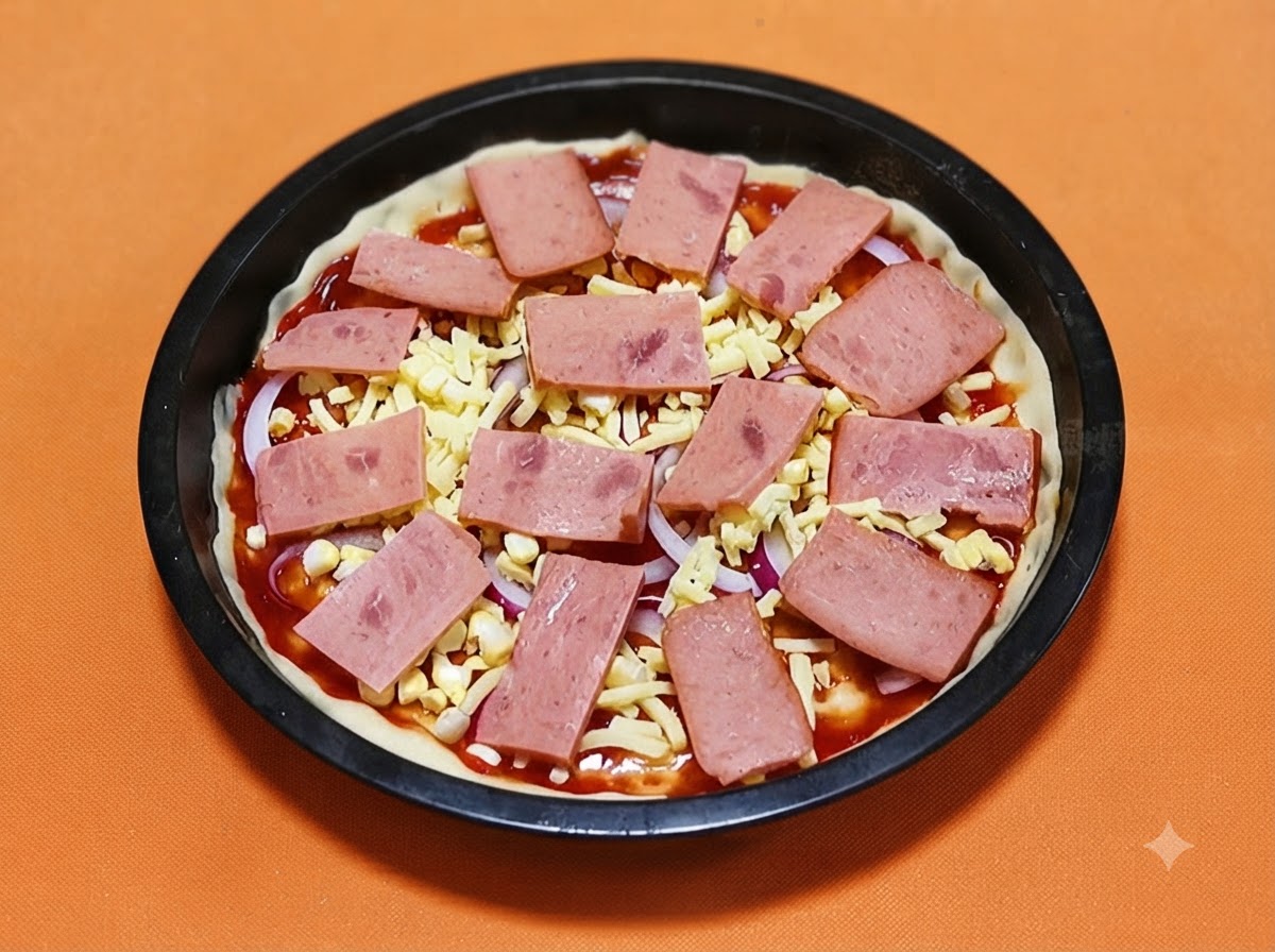 Tranches rectangulaires de jambon rose disposees systematiquement sur une croute de pizza garnie de fromage et doignons.