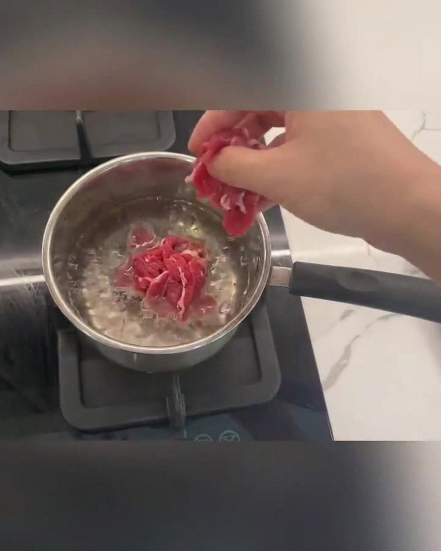 Tranches de bœuf cuisant dans de leau bouillante avec de la mousse à la surface.