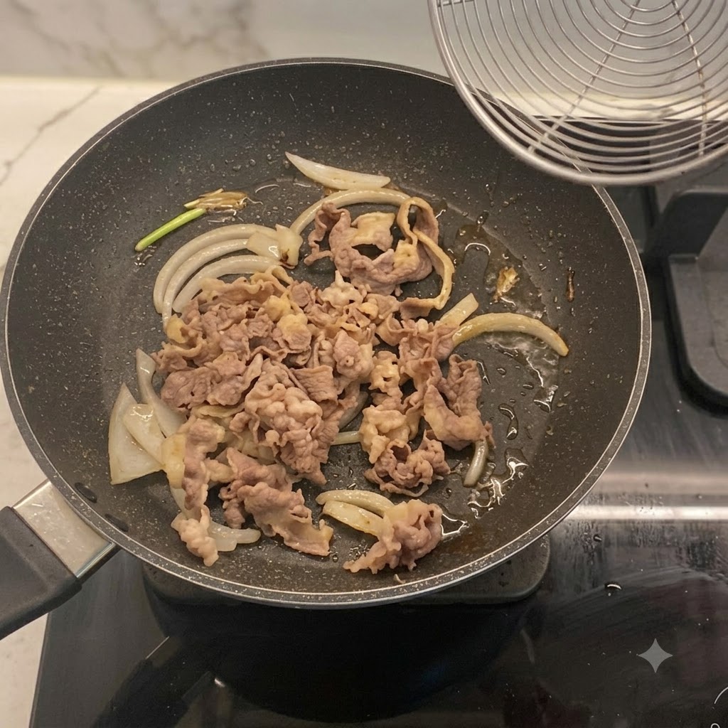 Tranches de bœuf blanchies mélangées avec des oignons dans une poêle.