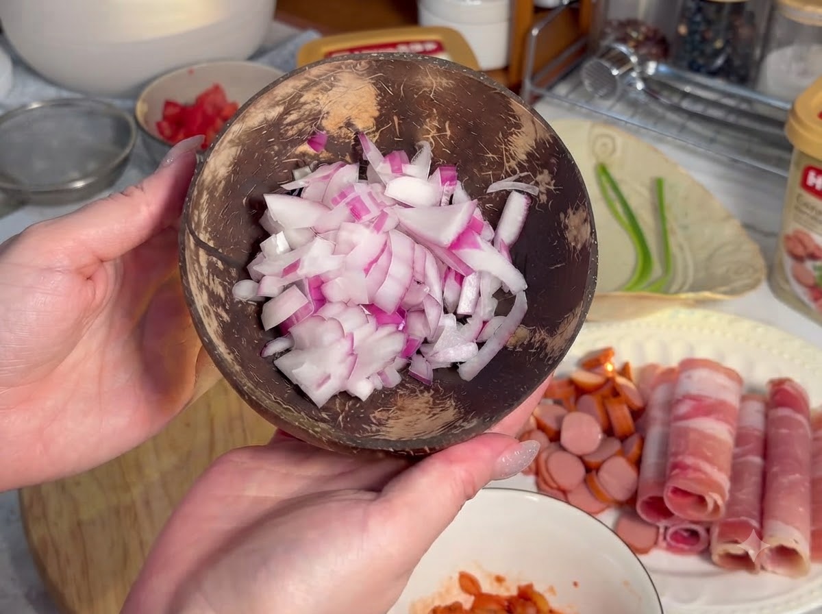 Saucisses coupées en petites rondelles disposées sur une planche en bois à côté de viande roulée.