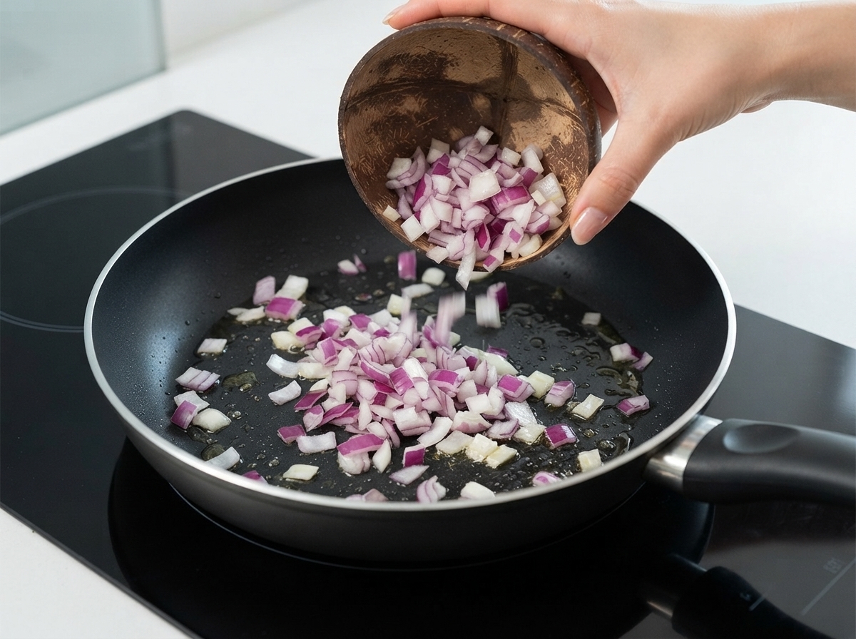 Oignons rouges en dés versés depuis un bol en coco dans une poêle avec de lhuile.