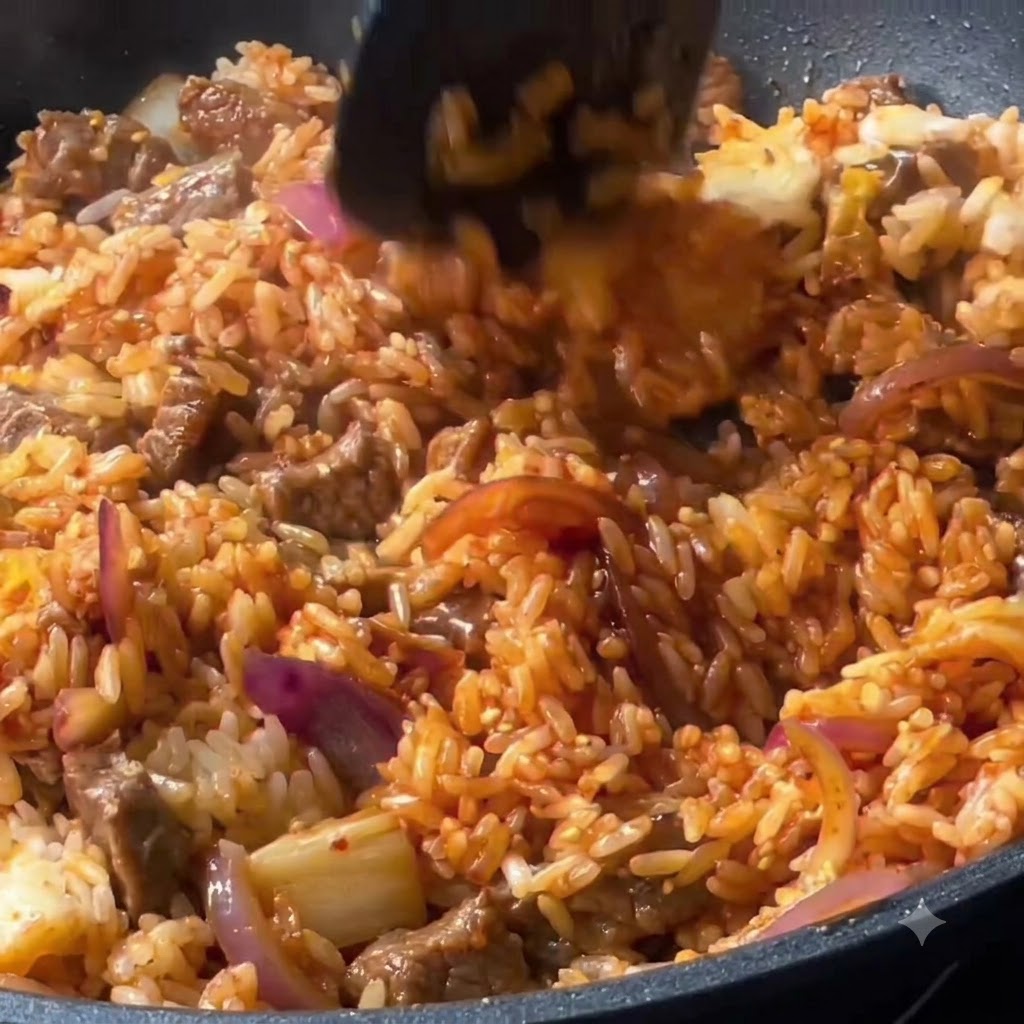 Riz, bœuf et légumes mélangés soigneusement avec une spatule dans la poêle.