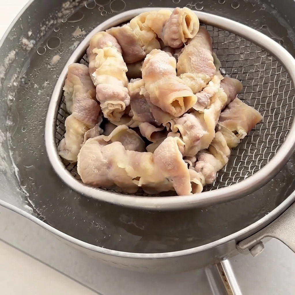 Écumoire retirant les tranches de bœuf précuites de la casserole deau chaude.