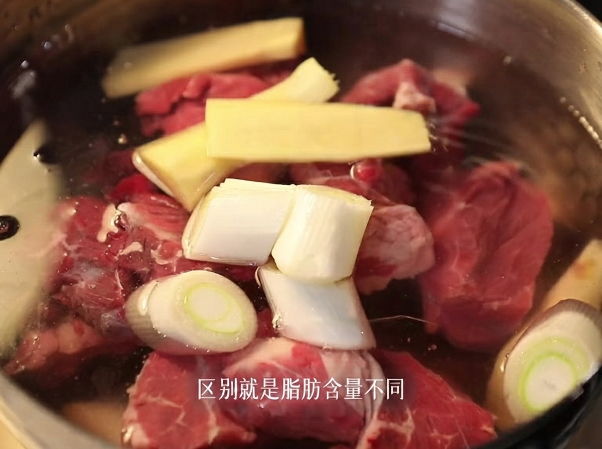 Des morceaux de poitrine de bœuf crus submergés dans une casserole deau froide avec du gingembre tranché et des oignons verts.