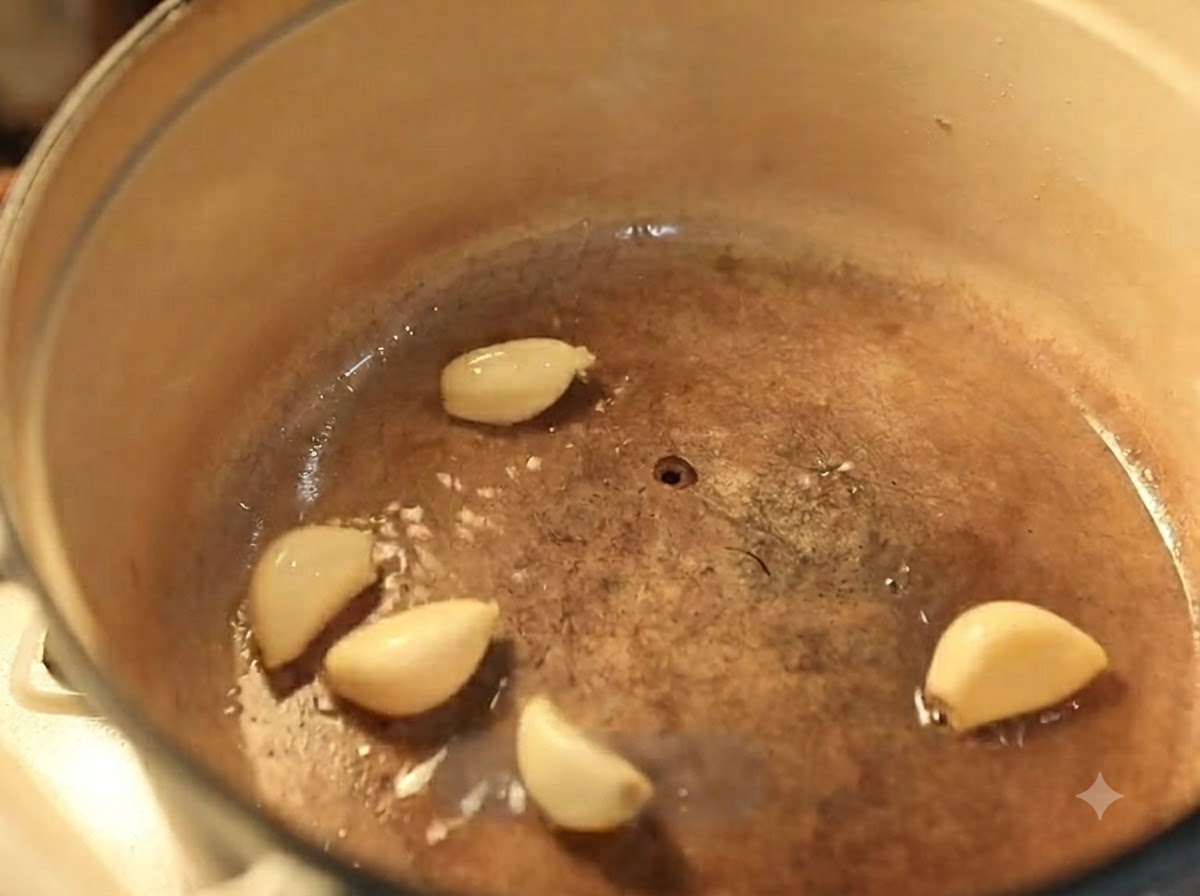Des gousses dail frisant dans de lhuile chaude à lintérieur dune cocotte en fonte émaillée.