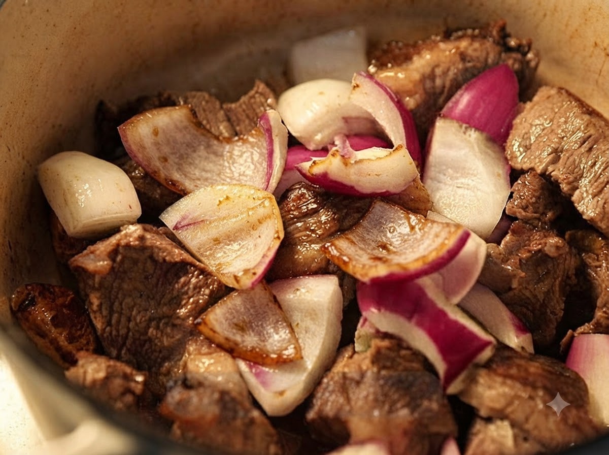 Des oignons rouges hachés mélangés au bœuf doré dans la cocotte.