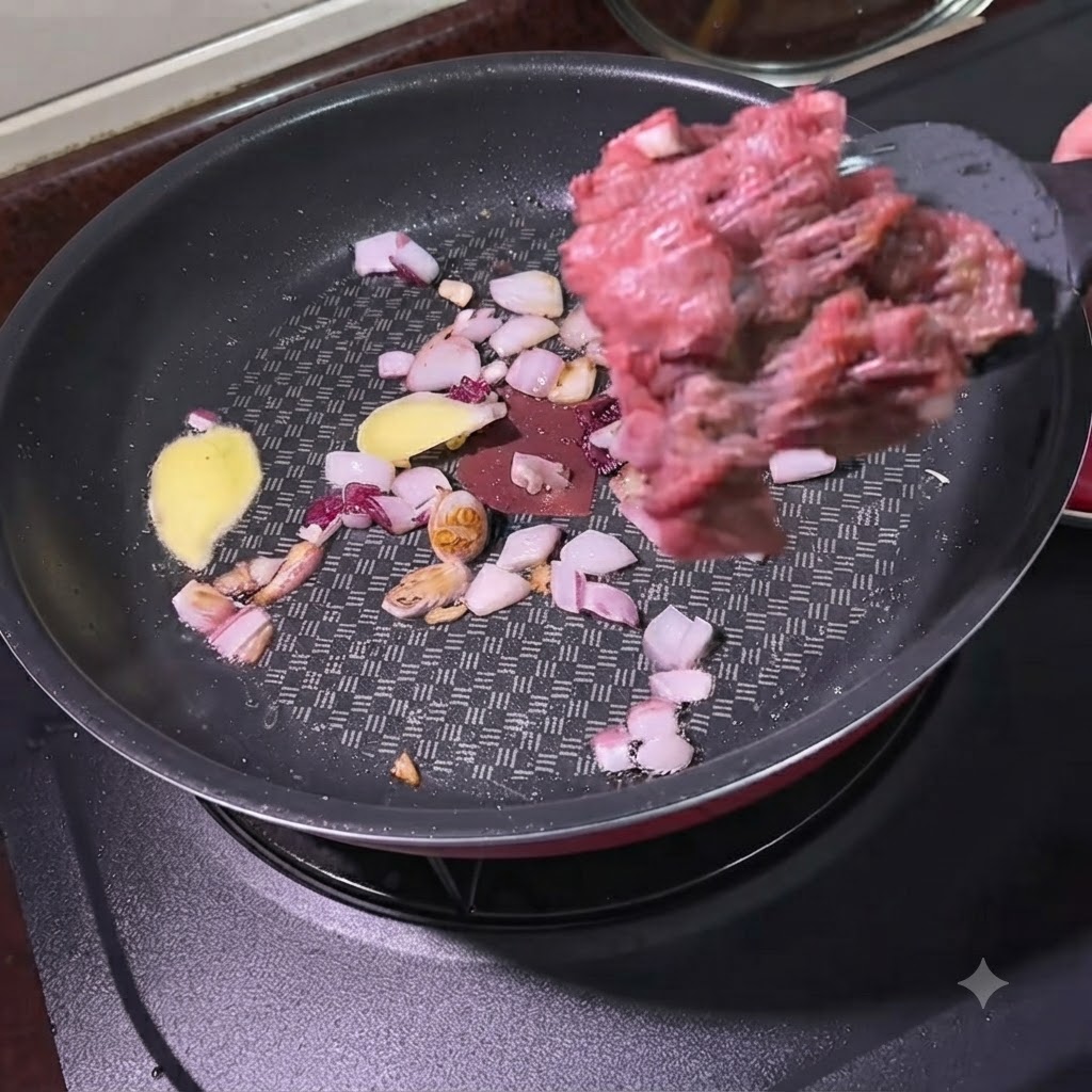 Du bœuf haché ajouté à laide dune spatule dans une poêle contenant des oignons sautés et des tranches de gingembre.