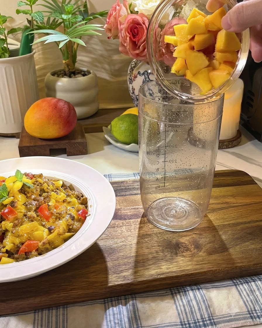Des morceaux de pêche fraîche, du miel et des tranches de citron versés dans un grand verre à mélange transparent.