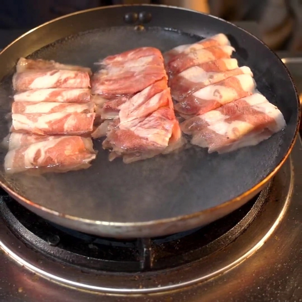Des rouleaux de bœuf bouillant dans une casserole avec du vin de cuisine ajouté à leau.