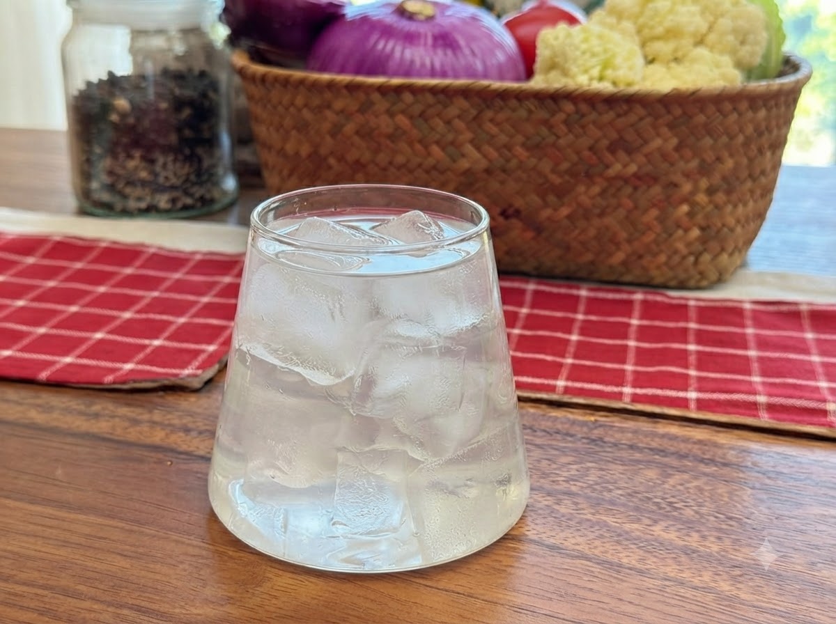 De leau de coco versée dans un verre transparent rempli de glaçons.