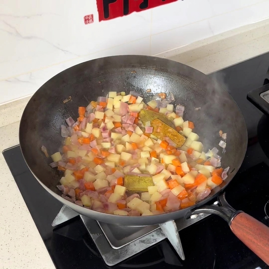 Pommes de terre et carottes en dés en train dêtre mélangées avec des oignons à lintérieur dun wok.