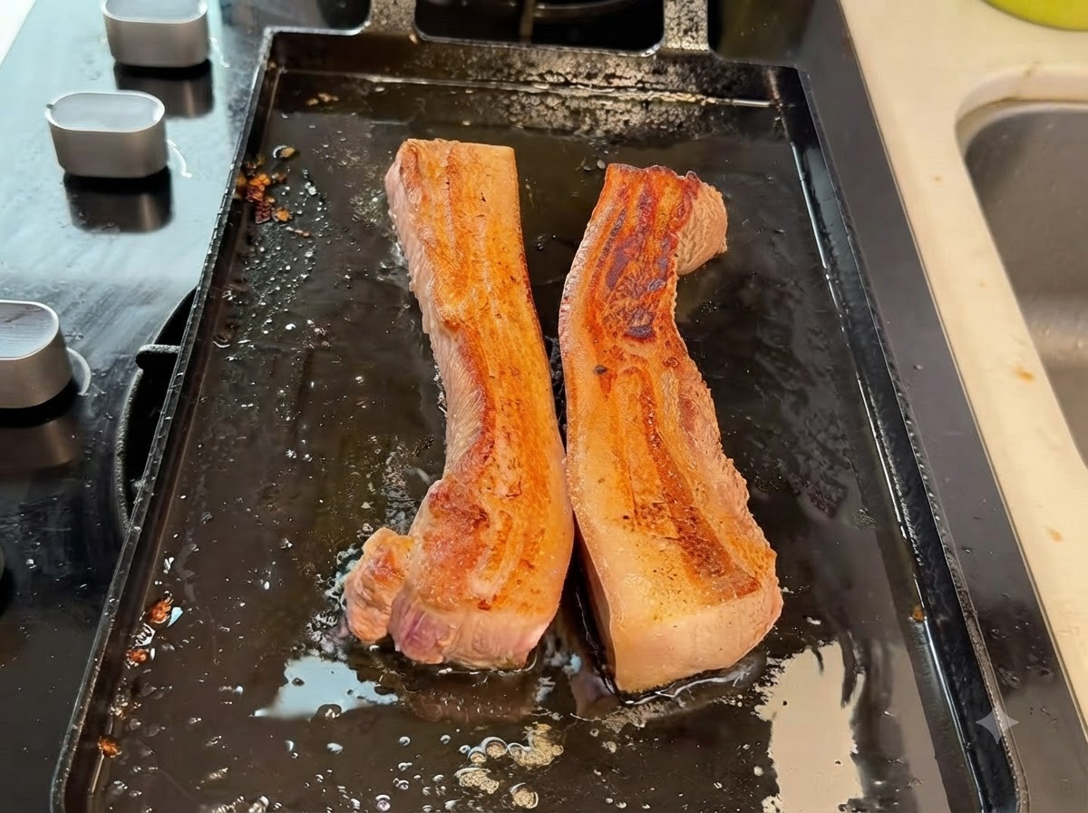 Des lanières épaisses de poitrine de porc coupées en morceaux plus petits à laide de ciseaux de cuisine sur la plaque.