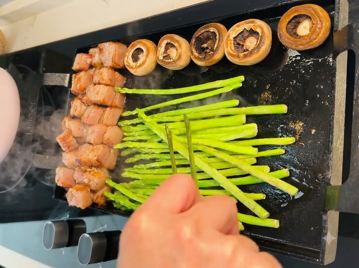 Des épis de maïs et des grappes de tomates cerises disposés sur la poêle teppanyaki.