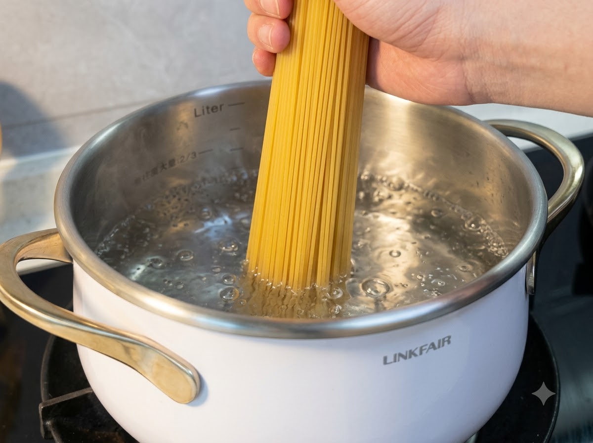 Une main tenant des nouilles de riz sèches alors quelles sont immergées dans une casserole deau bouillante.