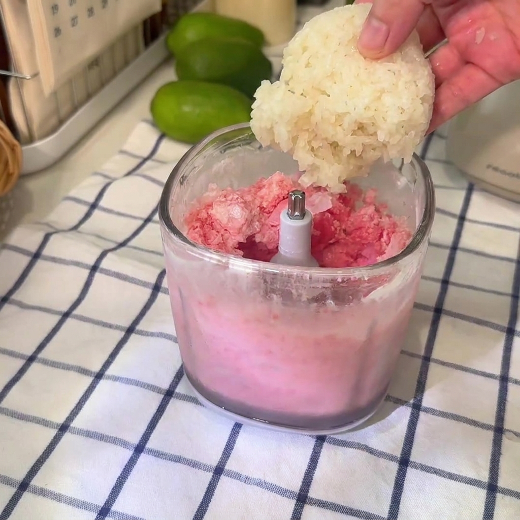 Une boule de riz gluant ajoutée dans un gobelet de blender transparent rempli du mélange de granité à la pastèque.