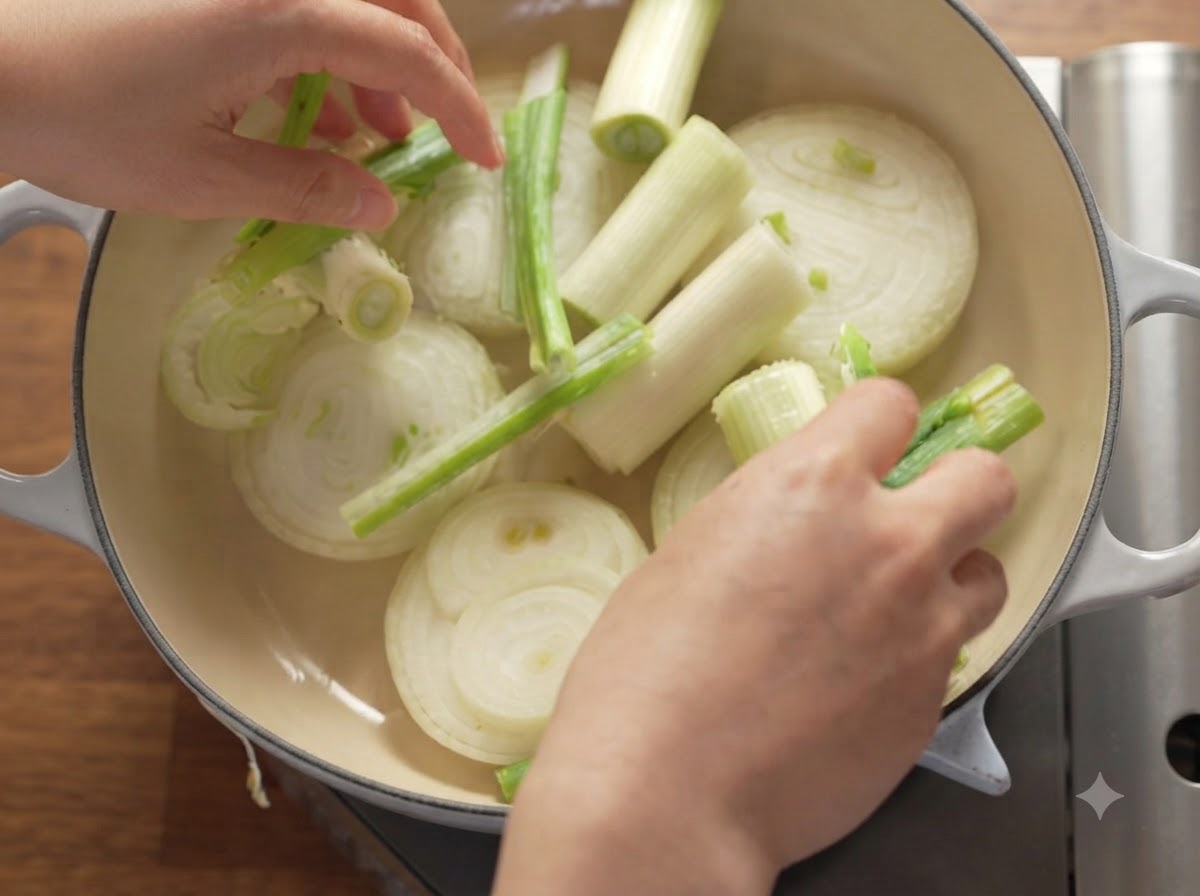 Tranches doignons, doignons verts et de pommes disposées proprement à lintérieur dune cocotte en fonte lourde.